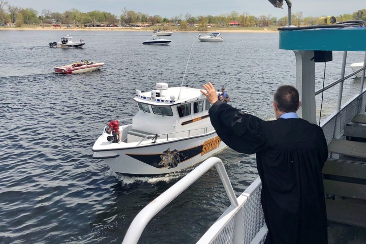 a man standing in front of a boat next to a body of water