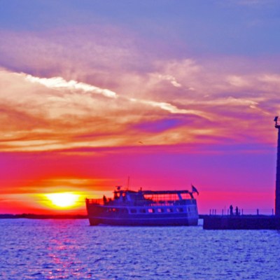 a sunset over a body of water with a city in the background