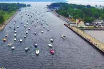 Aerial view of a canal with many small boats, surrounded by greenery and docks.